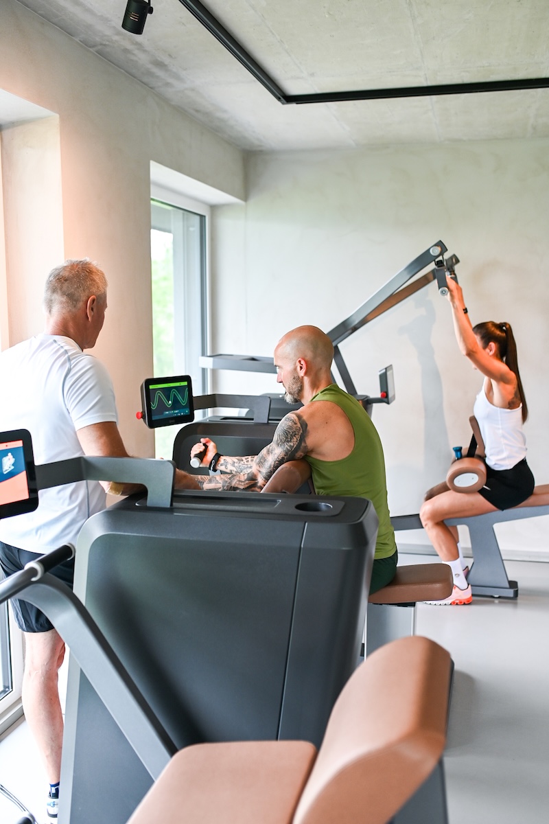 Gruppenaufnahme, drei Personen trainieren an Geräten